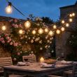 Festoon Lights With Warm White Bulbs Over A Long Garden Dinner Party Table With Candles And Flowers At Night