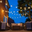 Festoon Lights With Warm White Bulbs Over A Long Garden Dinner Party Table With Candles And Flowers At Night
