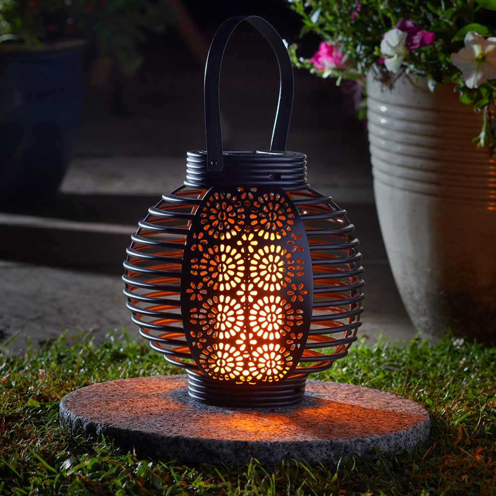 Ferrara Flaming Solar Garden Lantern on garden table at night