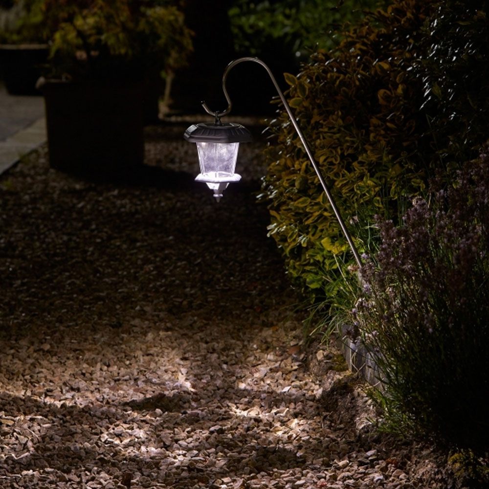 Hansom Carriage Lantern (2 Pack) in garden flower bed at an angle