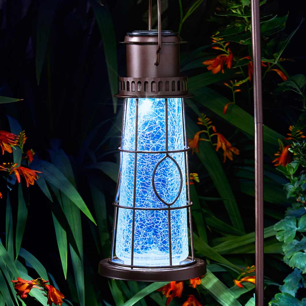 solar powered lighthouse lantern hanging in garden at night close up of light